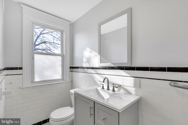 bathroom with vanity, tile walls, and toilet