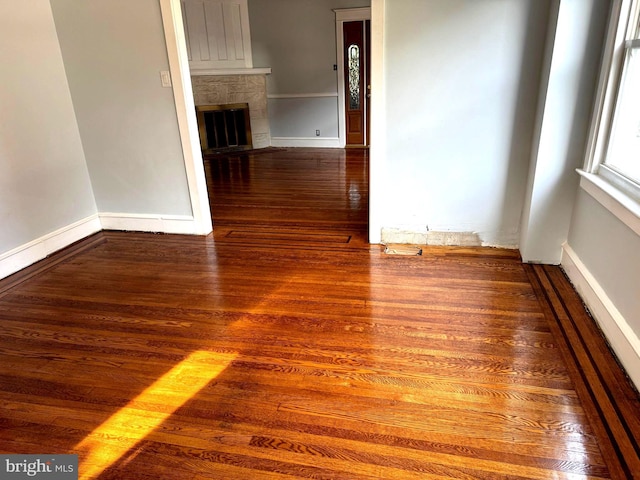 spare room with dark hardwood / wood-style flooring and a tiled fireplace