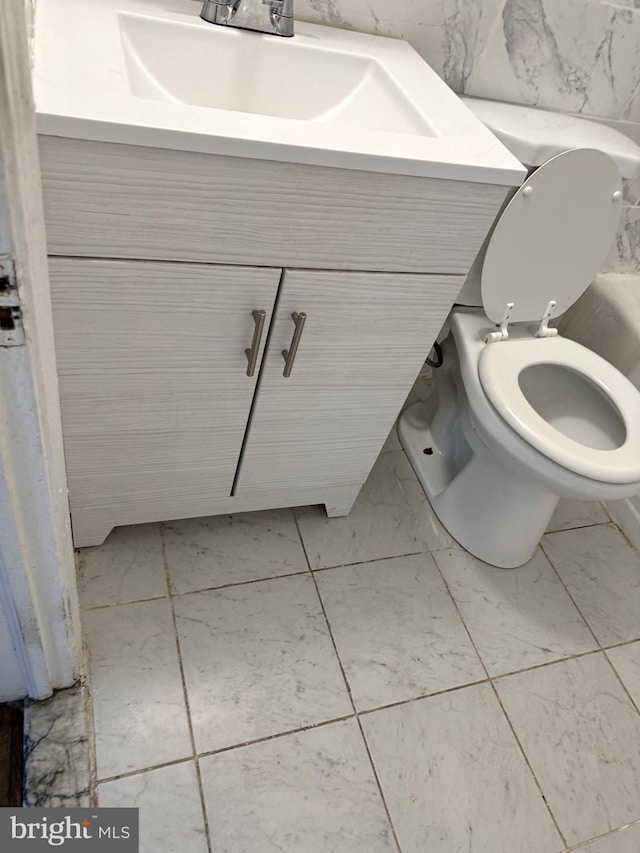 bathroom featuring vanity, toilet, and tile walls