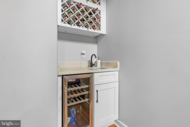 bar featuring wine cooler, white cabinetry, and sink