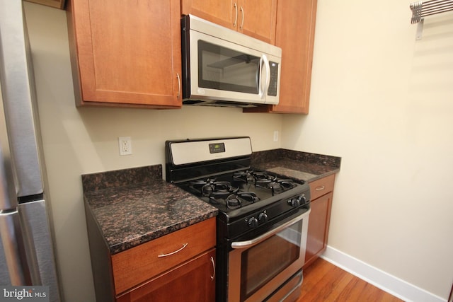 kitchen with gas stove, dark stone counters, and light hardwood / wood-style floors