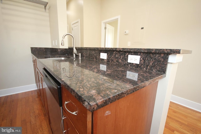 kitchen featuring hardwood / wood-style flooring, dark stone countertops, sink, and dishwasher