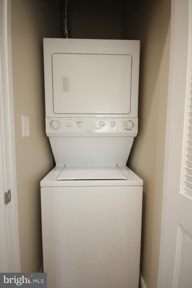 clothes washing area with stacked washer / dryer