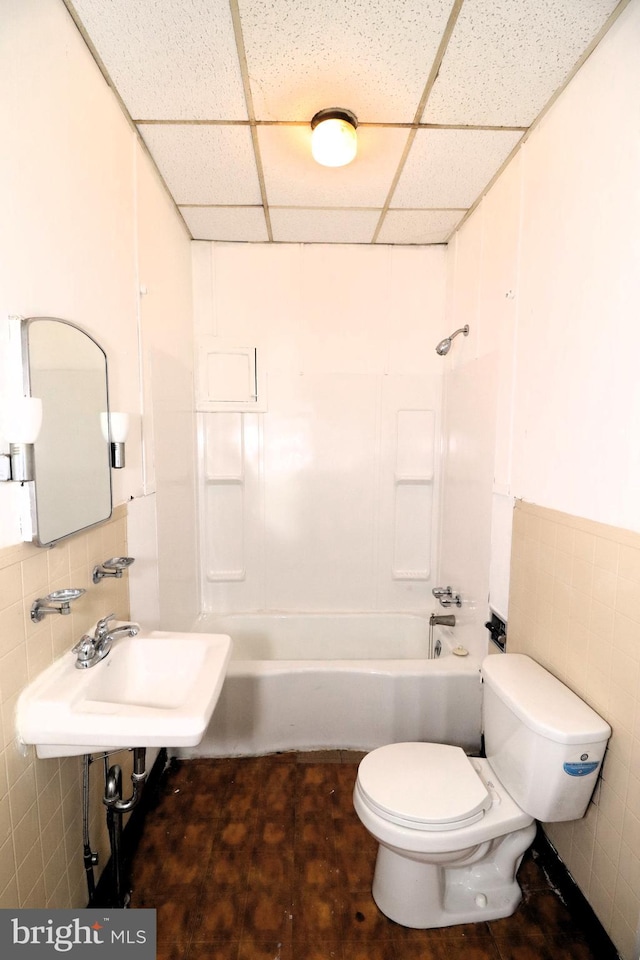 full bathroom featuring tile walls, shower / bathtub combination, and a drop ceiling