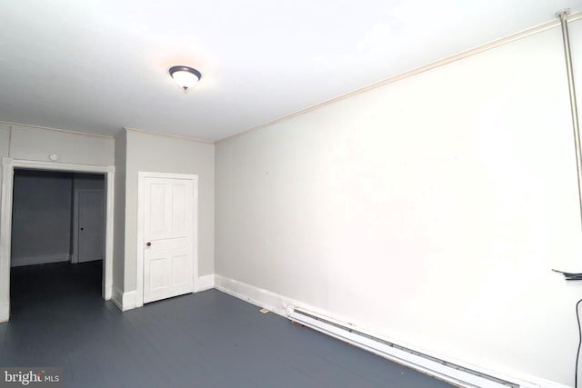 empty room with dark hardwood / wood-style floors, a baseboard radiator, and crown molding