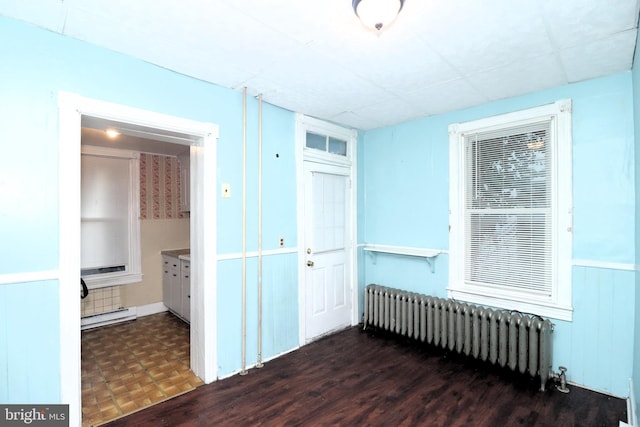 unfurnished room with a baseboard heating unit, radiator heating unit, and dark wood-type flooring