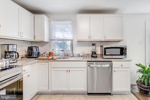 kitchen with light hardwood / wood-style flooring, light stone countertops, appliances with stainless steel finishes, and white cabinets