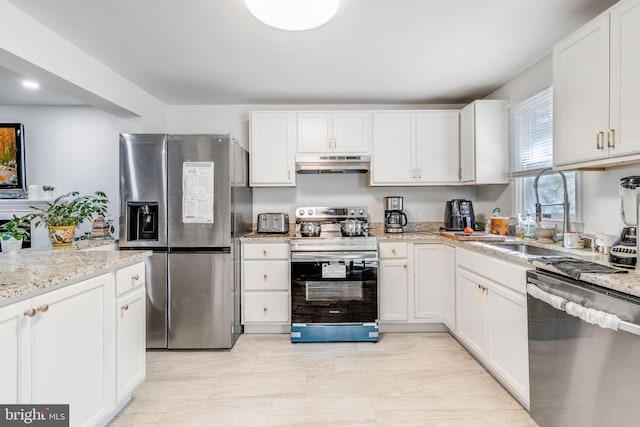 kitchen with stainless steel appliances, light stone countertops, white cabinetry, and sink