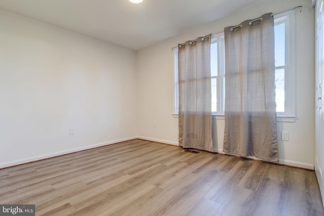 unfurnished room featuring a wealth of natural light and light hardwood / wood-style floors