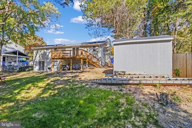 back of property with a storage unit, a wooden deck, and a yard