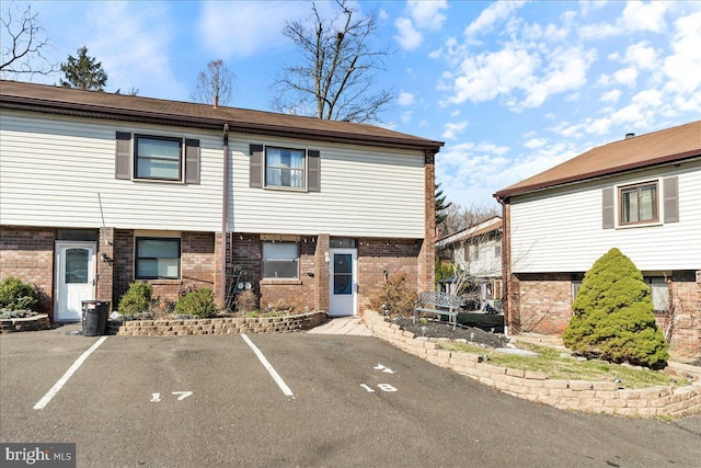 view of property featuring brick siding and uncovered parking