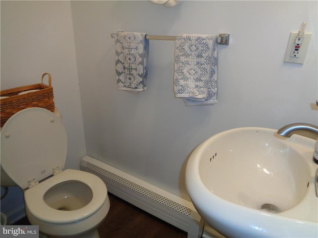 bathroom with sink, a baseboard heating unit, and toilet