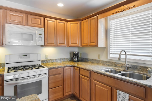 kitchen with white appliances, sink, and stone countertops