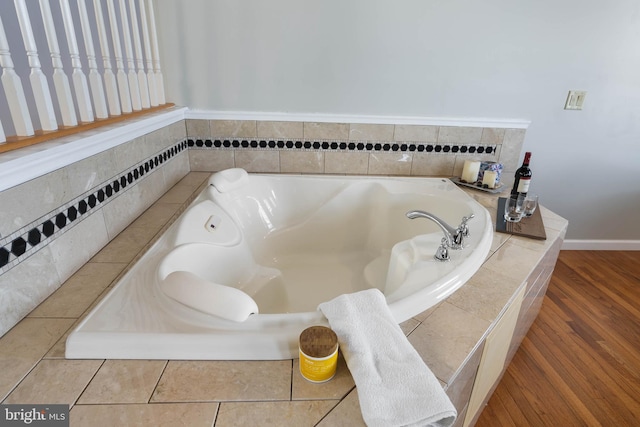 bathroom with wood-type flooring and tiled tub