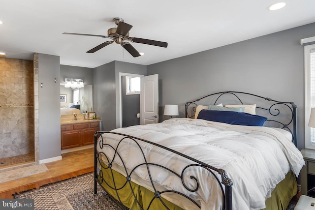 bedroom featuring hardwood / wood-style flooring, ceiling fan, ensuite bath, and sink