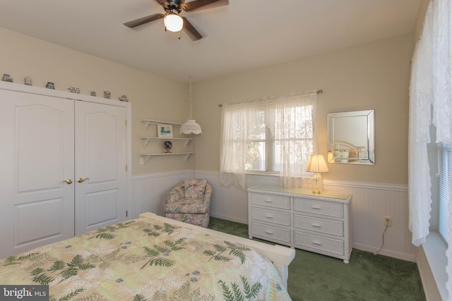 bedroom with dark colored carpet, ceiling fan, and a closet