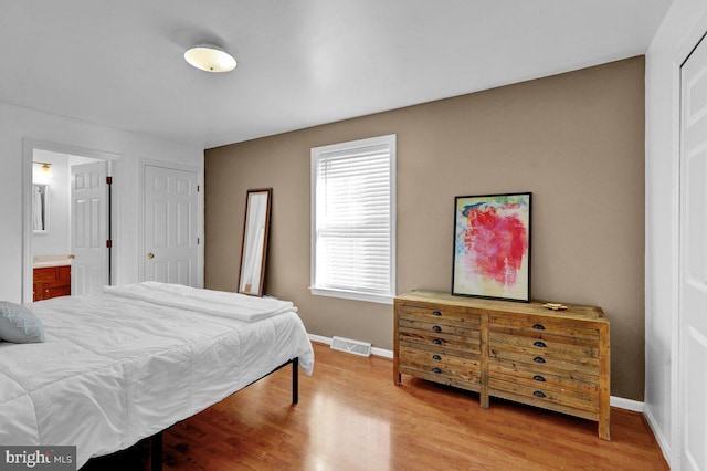 bedroom with ensuite bathroom and light wood-type flooring