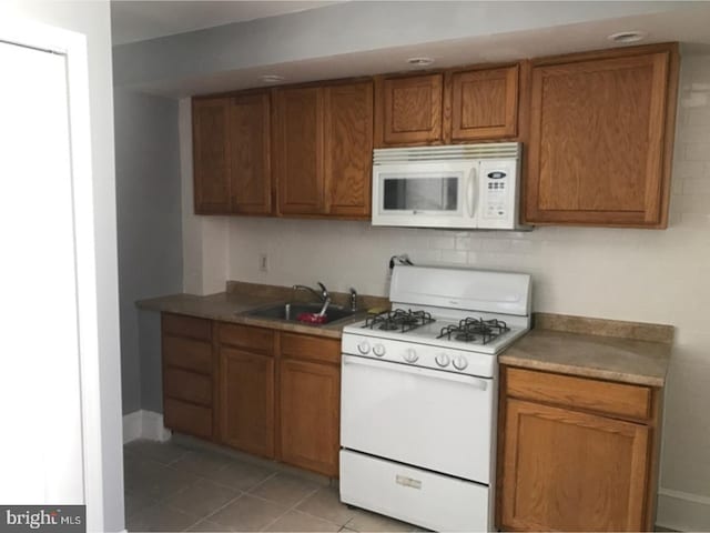 kitchen featuring light tile patterned flooring, decorative backsplash, white appliances, and sink