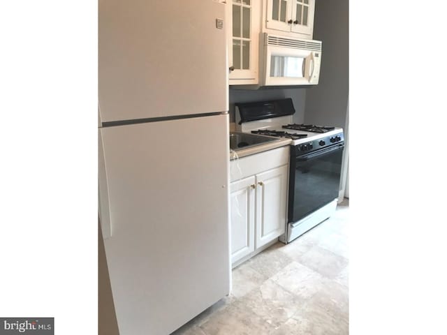 kitchen featuring white cabinets and white appliances