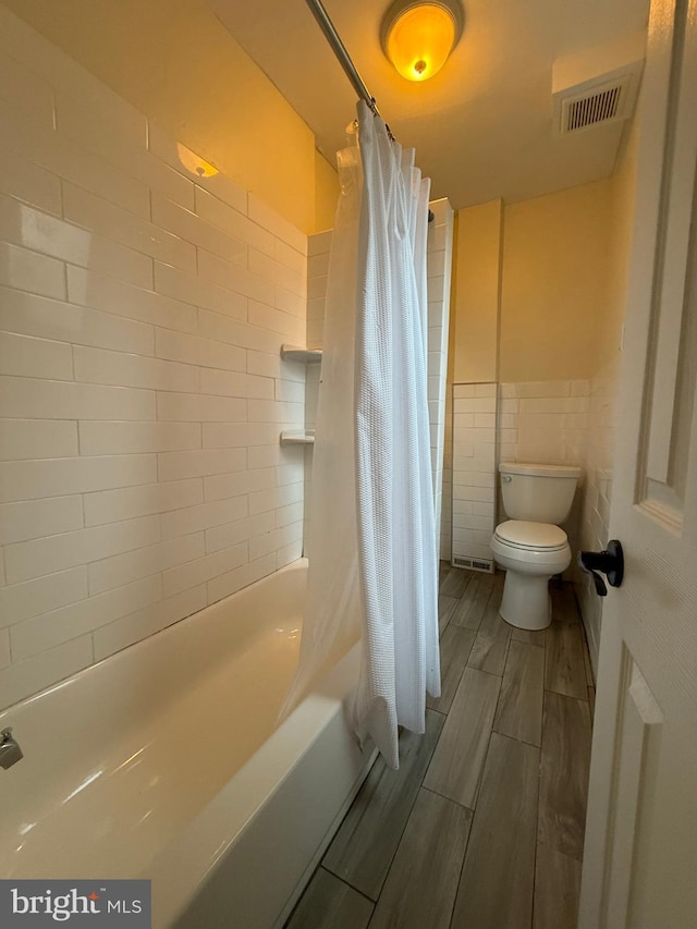 bathroom with shower / bathtub combination with curtain, tile walls, and toilet