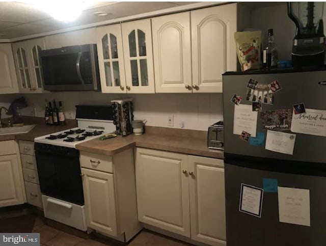 kitchen with appliances with stainless steel finishes, tasteful backsplash, white cabinetry, and sink