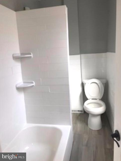 bathroom with hardwood / wood-style flooring, toilet, and tub / shower combination