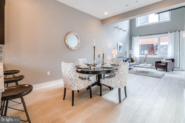 dining space featuring a high ceiling and light wood-type flooring