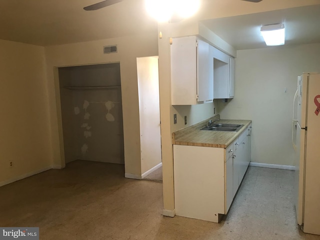 kitchen featuring white cabinets, sink, ceiling fan, and white fridge