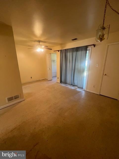 empty room featuring ceiling fan with notable chandelier