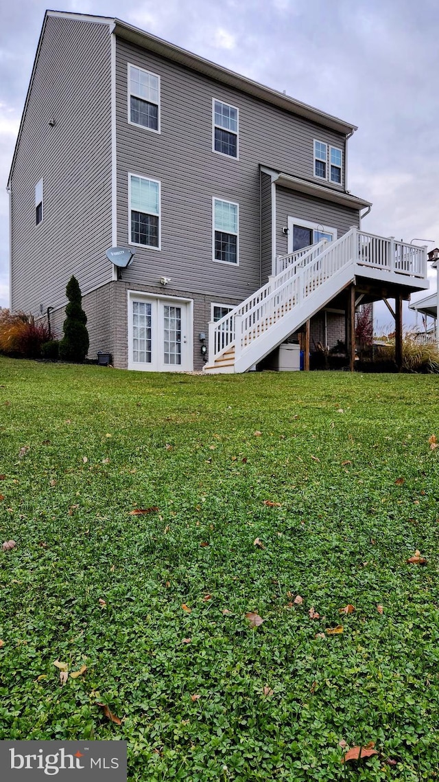 rear view of house with a wooden deck and a lawn