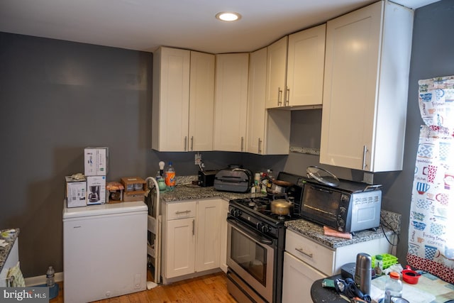 kitchen featuring stainless steel range with gas stovetop, stone countertops, light wood-style floors, fridge, and recessed lighting