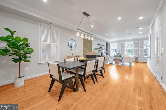 dining room featuring light wood-type flooring and crown molding