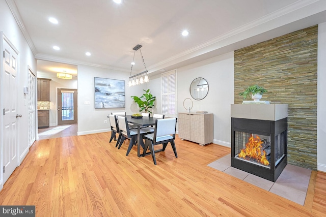 dining area featuring a multi sided fireplace, light hardwood / wood-style flooring, and ornamental molding