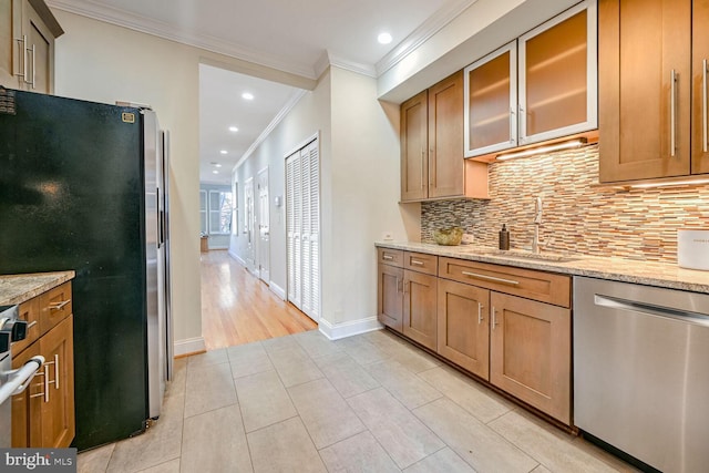 kitchen with sink, light stone counters, appliances with stainless steel finishes, and ornamental molding