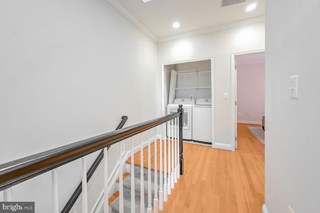 hallway with washing machine and clothes dryer, light hardwood / wood-style floors, and crown molding