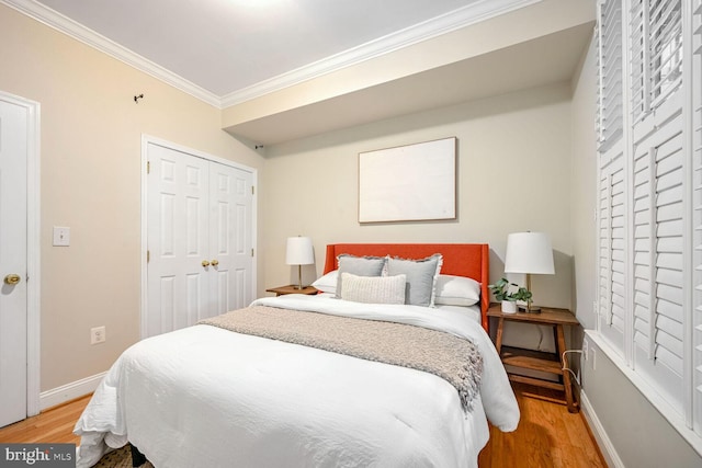 bedroom with a closet, light wood-type flooring, and crown molding