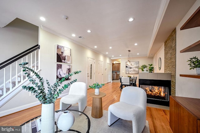 living room featuring a multi sided fireplace, ornamental molding, and light hardwood / wood-style flooring