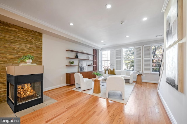 living room featuring a multi sided fireplace, crown molding, and light hardwood / wood-style flooring