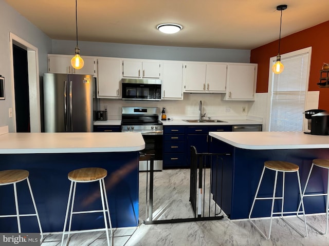 kitchen with white cabinetry, sink, hanging light fixtures, a breakfast bar area, and appliances with stainless steel finishes