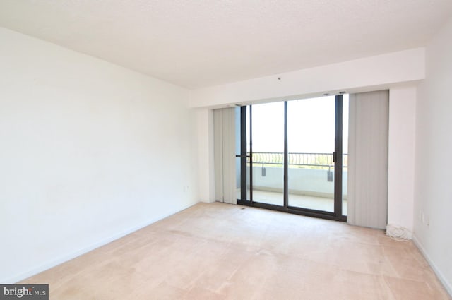 empty room with light carpet, baseboards, and a textured ceiling