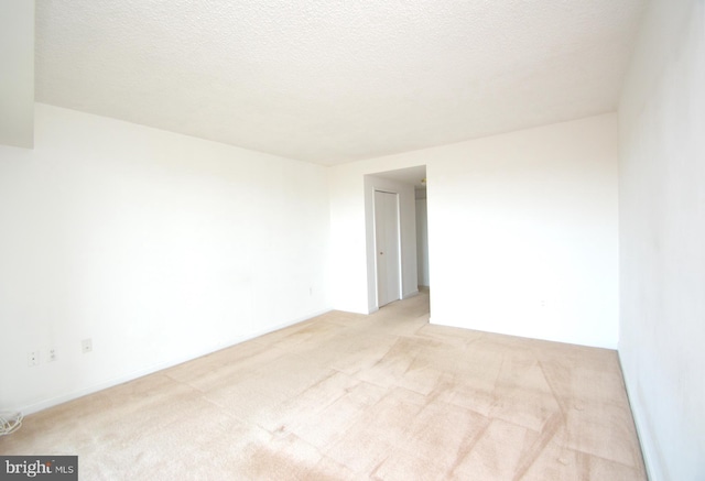 empty room with a textured ceiling and light colored carpet