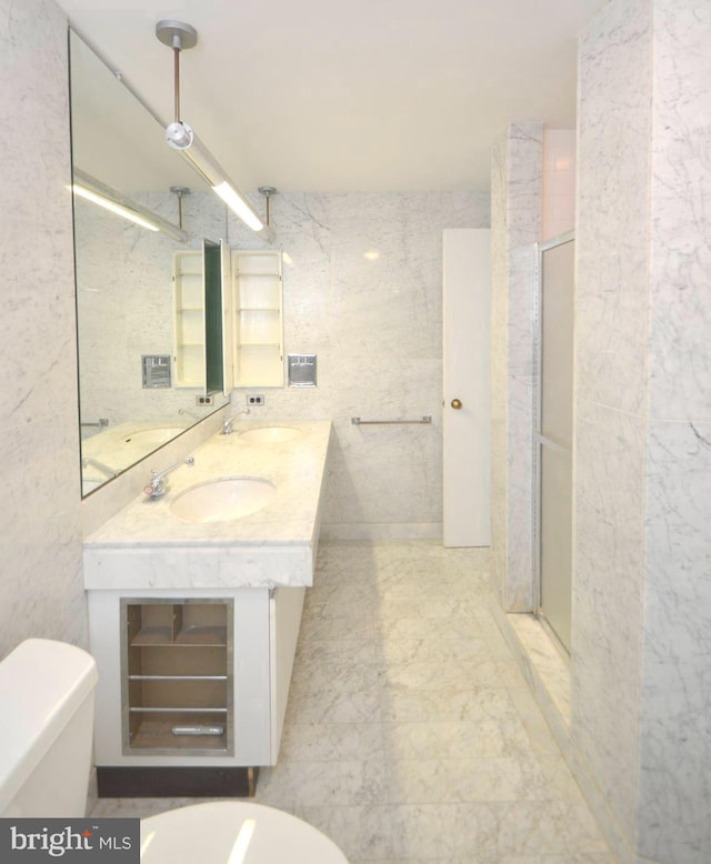 bathroom featuring a stall shower, a sink, tile walls, and toilet