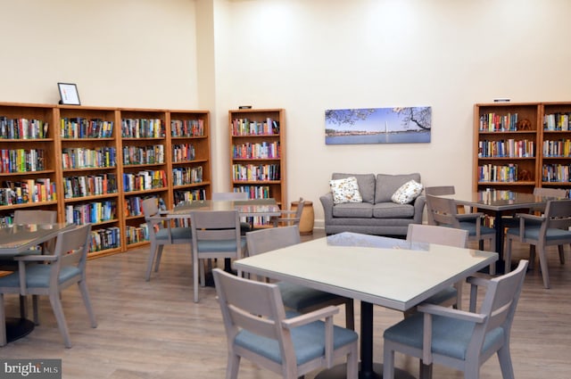 sitting room with wall of books and wood finished floors