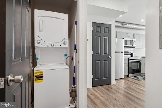 laundry area with stacked washing machine and dryer, light wood finished floors, and recessed lighting