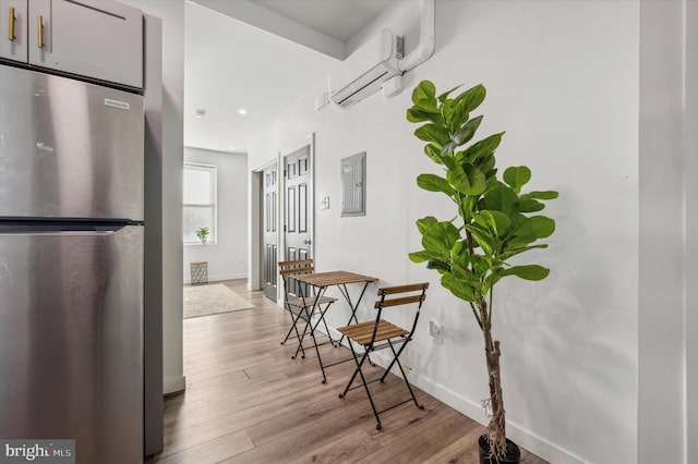 hallway with a wall mounted air conditioner, electric panel, and light hardwood / wood-style flooring