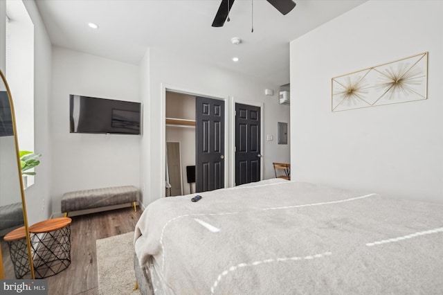 bedroom with electric panel, hardwood / wood-style flooring, and ceiling fan