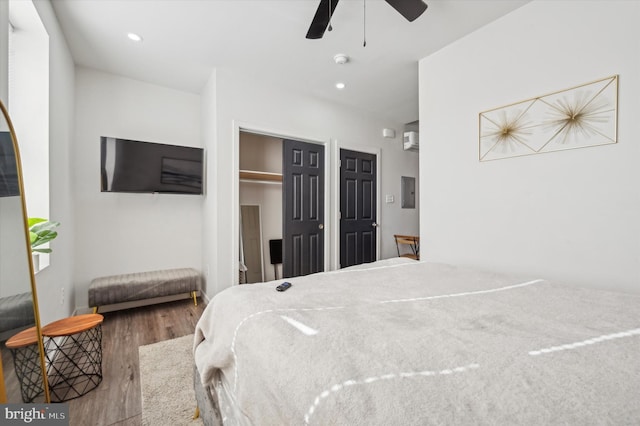 bedroom featuring wood finished floors, electric panel, recessed lighting, a wall mounted AC, and a ceiling fan