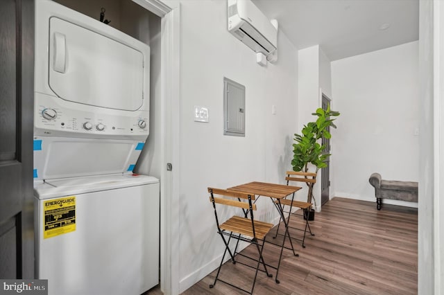 washroom featuring stacked washer / dryer, a wall unit AC, wood finished floors, electric panel, and baseboards
