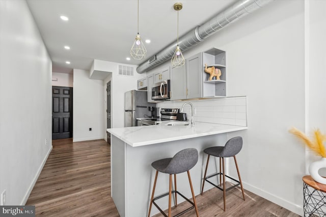 kitchen with pendant lighting, decorative backsplash, kitchen peninsula, and stainless steel appliances