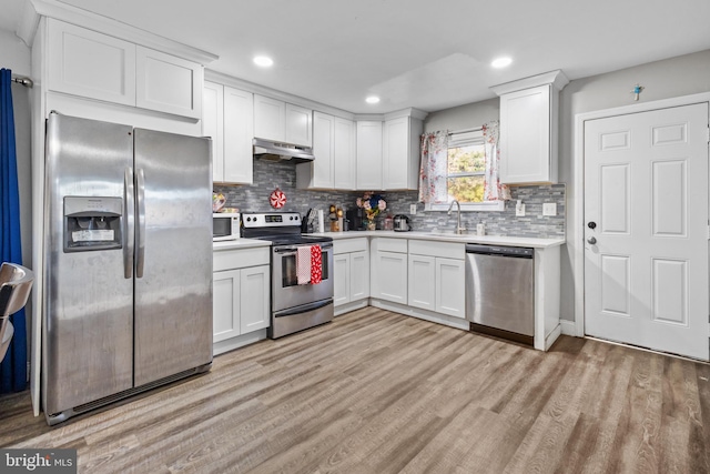 kitchen with white cabinetry, light wood-type flooring, appliances with stainless steel finishes, and exhaust hood